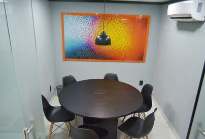 Sala de Reunião Black com mesa redonda escura, cadeiras pretas e quadro colorido