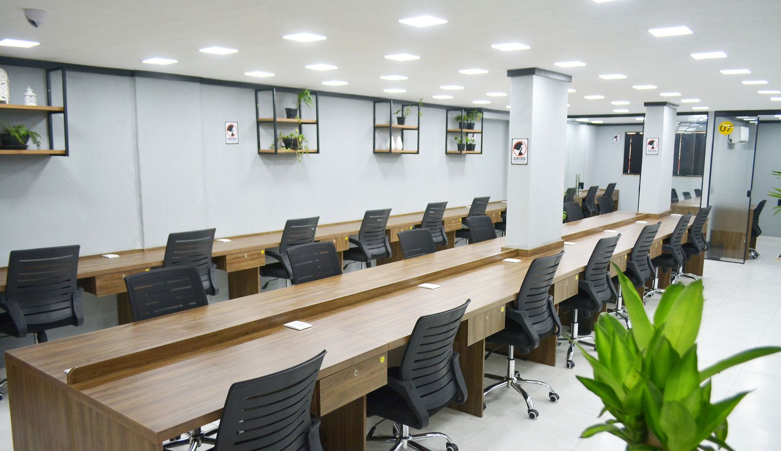 Salão de estações compartilhadas do DG Coworking, com bancadas de madeira e iluminação embutida